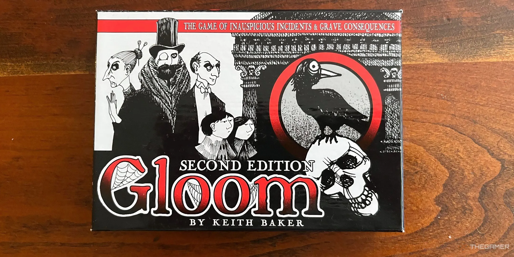 Hộp board game Gloom với hình ảnh gia đình u sầu, gothic, trên nền trong suốt độc đáo.