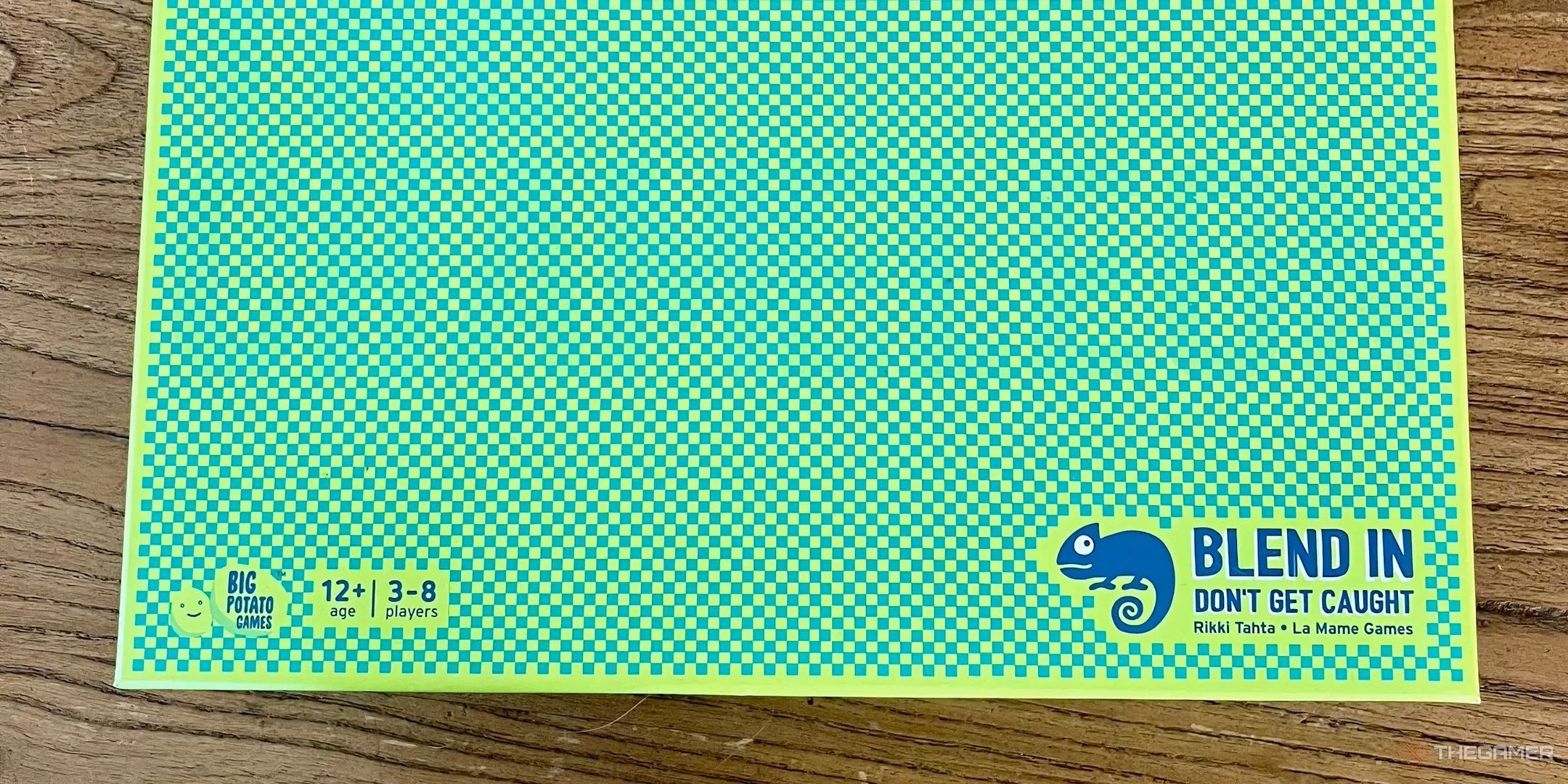 Hộp board game The Chameleon với biểu tượng con tắc kè trên nền xanh lá.