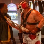 Sweet Tooth cầm dao dính máu đe dọa John Doe trong phim Twisted Metal.